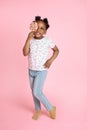 Full length portrait of adorable cute little African American girl holding lollipop candy, covering her eye, posing to Royalty Free Stock Photo