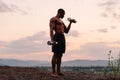 Full-length portrait of african american muscular athlete lifting dumbbells against the sunset sky background Royalty Free Stock Photo
