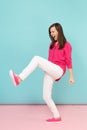 Full length portrait of angry fun young pretty woman in rose shirt blouse, white pants posing isolated on bright pink