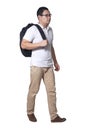 Full length portrait of Asian man wearing white shirt, khaki jeans and backpack standing walking, side view Royalty Free Stock Photo