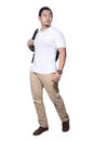 Full length portrait of Asian man wearing white shirt, khaki jeans and backpack standing walking, side view Royalty Free Stock Photo