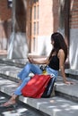 Portrait of Asian woman sitting on stairs with shopping bags and using smart phone. Royalty Free Stock Photo