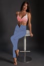 Full-length portrait of an attractive woman in fashionable cartoon jeans and sensual lingerie posing sitting on a bar Royalty Free Stock Photo