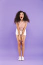 Full length portrait of attractive woman with curly hair in summer wear laughing at camera, isolated over violet background in st Royalty Free Stock Photo