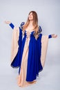 A full-length portrait of an attractive woman with long hair in a medieval, fantasy, blue and beige dress with long, large sleeves Royalty Free Stock Photo