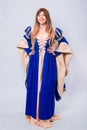 A full-length portrait of an attractive woman with long hair in a medieval, fantasy, blue and beige dress with long, large sleeves Royalty Free Stock Photo