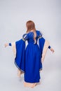 A full-length portrait of an attractive woman with long hair standing back in a medieval, fantastic, blue and beige dress Royalty Free Stock Photo