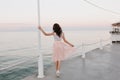 Full-length portrait from back of elegant brunette girl walking along the ocean wharf and enjoying beautiful morning Royalty Free Stock Photo