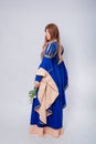 Full-length portrait, back view, attractive woman in medieval, fantasy blue-beige dress with long, flared sleeves Royalty Free Stock Photo