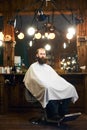 Male client with beard sitting in hairdresser chair. Serious man with long brown beard. Modern popular lumberjack style. Royalty Free Stock Photo