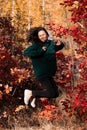 Full-length portrait of a beautiful Asian young woman jumping in an autumn forest at sunset