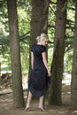 Full length portrait of beautiful barefooted young women wearing black dress while standing under pine tree