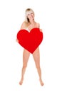 Full length portrait of a beautiful blonde woman wearing white lingerie and holding a big red heart Royalty Free Stock Photo