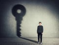 Full length portrait of beautiful businesswoman, casting a key shadow on the wall. Ambition and business success concept.