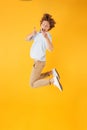 Full length portrait of beautiful curly man 20s jumping and show Royalty Free Stock Photo