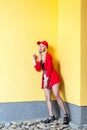 Full length portrait of beautiful fashion blonde young hipster woman in red blouse and cap posing near yellow wall Royalty Free Stock Photo