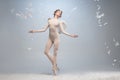 Full-length portrait of beautiful graceful ballerina dancing in image of angel with wings on gray studio