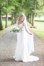 Full length portrait of beautiful sensual young blond bride in long white wedding dress and veil, holding bouquet Royalty Free Stock Photo