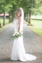 Full length portrait of beautiful sensual young blond bride in long white wedding dress and veil, holding bouquet Royalty Free Stock Photo