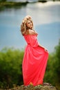 Full length portrait of beautiful sensual young blond woman near the lake outdoors in natural background. girl in long pink dress Royalty Free Stock Photo