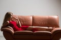 Full-length portrait of beautiful young blond woman on couch. long curly hair. Red dress Royalty Free Stock Photo