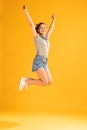 Full-length portrait of beautiful young girl in casual outfit jumping, posing isolated over yellow studio background Royalty Free Stock Photo