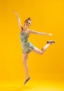 Full-length portrait of beautiful young girl posing, cheerfully jumping isolated over yellow studio background Royalty Free Stock Photo