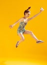 Full-length portrait of beautiful young girl posing in a jump isolated over yellow studio background Royalty Free Stock Photo