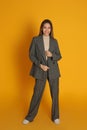 Full length portrait of beautiful young woman in fashionable suit on yellow background. Business attire Royalty Free Stock Photo