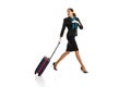 Full-length portrait of beautiful young woman, flight attendant running with suitcase isolated on white studio Royalty Free Stock Photo