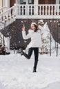 Full-length portrait of carefree girl standing on one leg and laughing in winter day. Outdoor photo of european young