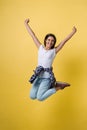 Full-length portrait of carefree girl in white shirt and jean jumping on yellow background. Royalty Free Stock Photo
