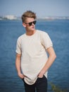 Stylish young man in sunglasses. Tall, cool guy walking near the river on a blurred background. College style concept. Royalty Free Stock Photo