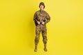 Full length portrait of charming satisfied girl standing hands hold tactical belt  on yellow color background Royalty Free Stock Photo