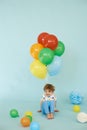 Full length portrait of cheerful boy holding balons posing against blue background
