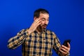 Full length portrait of a cheerful handsome young man standing isolated over blue background, holding mobile phone. Royalty Free Stock Photo