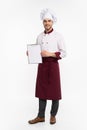 Full length portrait of a cheerful male chef cook in uniform holding blank board isolated on a white background.