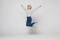 Full length portrait of a cheerful young woman jumping and celebrating over gray background Royalty Free Stock Photo