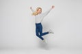 Full length portrait of a cheerful young woman jumping and celebrating over gray background Royalty Free Stock Photo