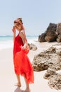 Full-length portrait of cheerful young woman playfully looking over shoulder on sea background. Pre Royalty Free Stock Photo