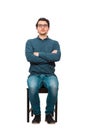 Full length portrait of confident businessman seated on a chair, wearing eyeglasses and keeps arms crossed, isolated on white Royalty Free Stock Photo