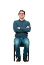 Full length portrait of confident businessman seated on a chair, wearing eyeglasses and keeps arms crossed, isolated on white Royalty Free Stock Photo