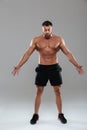 Full length portrait of a confident strong shirtless male bodybuilder