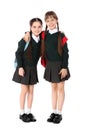 Full length portrait of cute girls in school uniform with backpacks on white Royalty Free Stock Photo