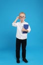Full length portrait of cute little boy with book on blue background Royalty Free Stock Photo