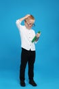 Full length portrait of cute little boy with book on blue background Royalty Free Stock Photo