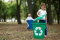 A little girl putting a bucket lid on a green recycling bin on a blurred natural background. Ecology and children. Royalty Free Stock Photo