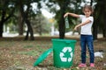 A little child putting the garbage in a green recycling bin on a blurred natural background. Ecology pollution concept. Royalty Free Stock Photo