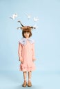 Full-length portrait of cute, lovely little girl, child in pink dress posing with paper birds above head against blue Royalty Free Stock Photo