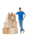 Full length portrait of delivery man standing near stack of boxes